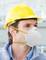 A construction worker wearing a yellow hard hat and white face mask is looking to the right. The background shows construction site elements.