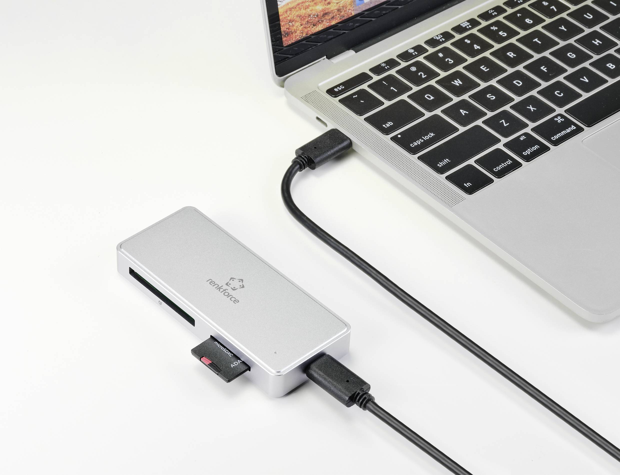 A laptop is connected via a USB-C hub with multiple ports, including USB and an SD card slot.
