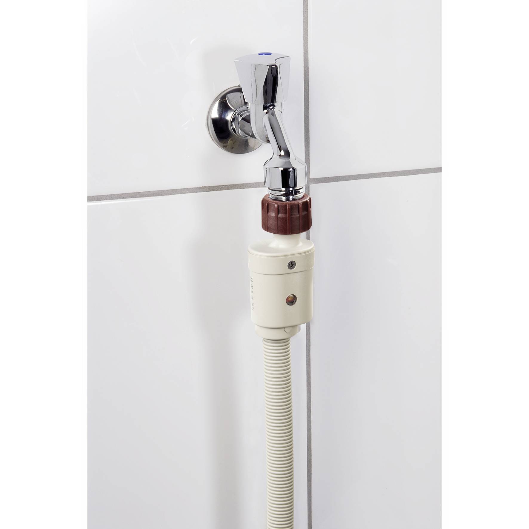 A chrome-plated wall-mounted tap with a connected white hose and safety system on a tiled surface.