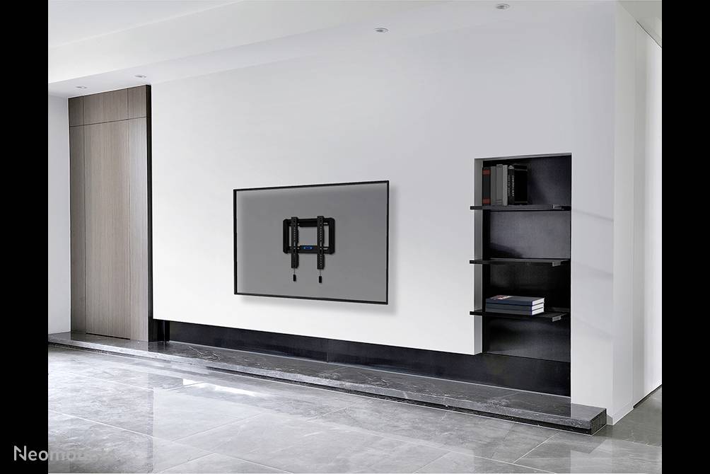 Flat-screen television mounted on a modern white wall, left side with wooden panelling, right side featuring built-in shelving with books.