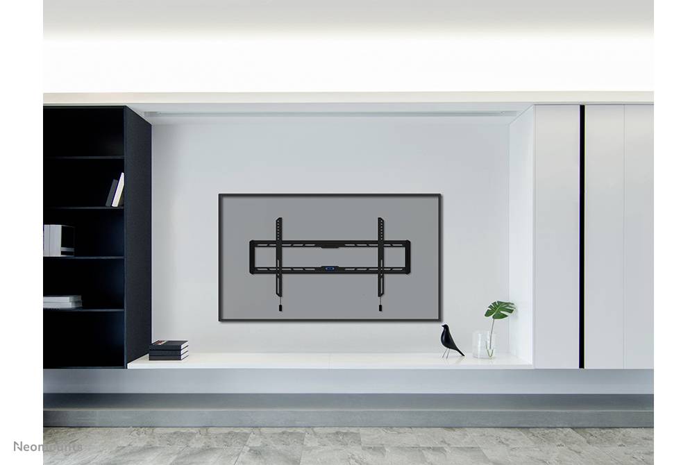 A blank, rectangular television frame on a white wall in a modern room, with decor and shelves beside it.