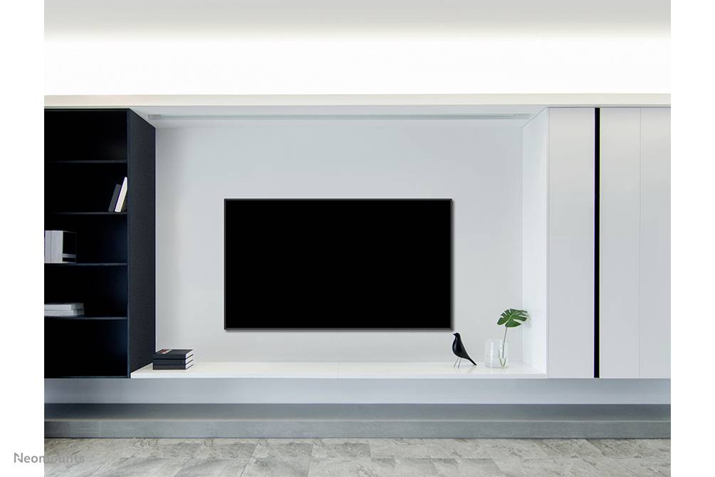 Modern living room interior with a large, black flatscreen television mounted on a white wall, with a shelving unit and a vase alongside it.