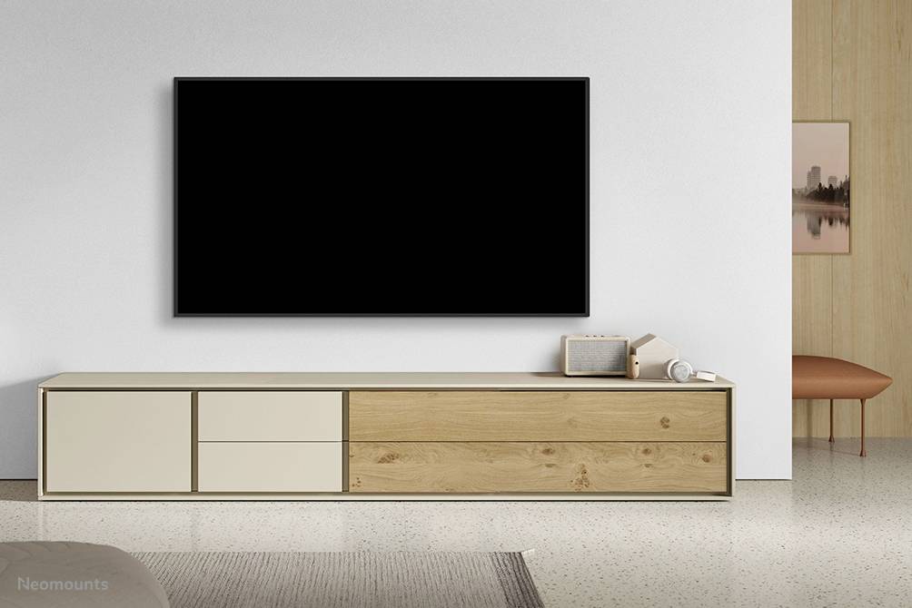A modern living room with a large, black television mounted on the wall. Beneath it stands a minimalist-designed sideboard.