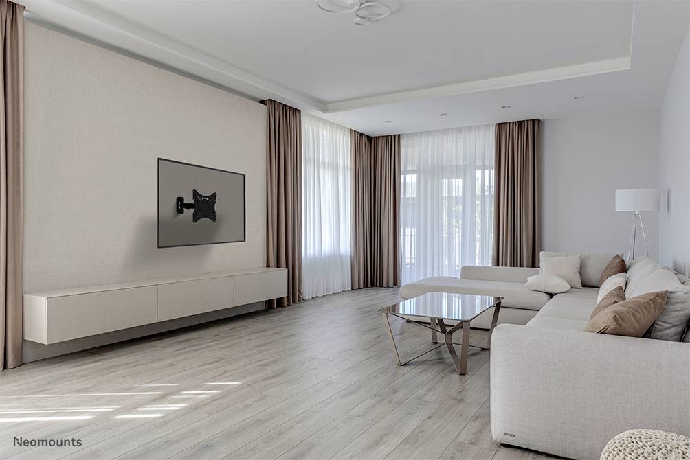 Minimalist living room with a cream-coloured sofa, glass coffee table, wall-mounted TV bracket and large windows with curtains.