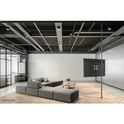 A modern office space with grey modular sofas on a wooden floor. A large screen is mounted on the right wall.