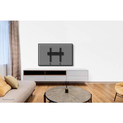 A modern living room with a wooden floor; a flatscreen television is mounted on the wall above a simple, white TV unit.