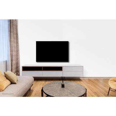 Living room with a beige sofa, round coffee table and wall-mounted flat-screen television above a low-level media unit. Minimalist interior design.