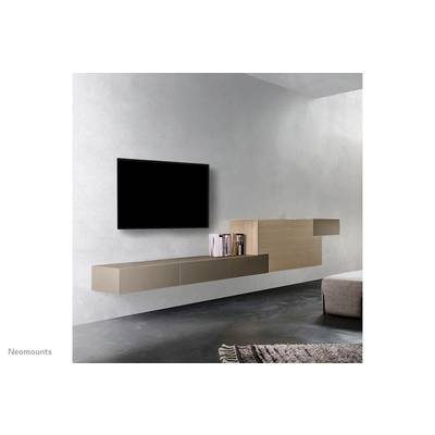A modern living room with a flat-screen television mounted on the wall and a floating shelf beneath it, displaying books.