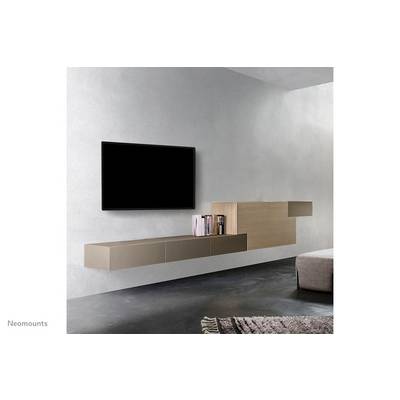 Television mounted on a grey wall, beside a stylish bookshelf with books. Carpet on dark flooring, creating a modern living room atmosphere.