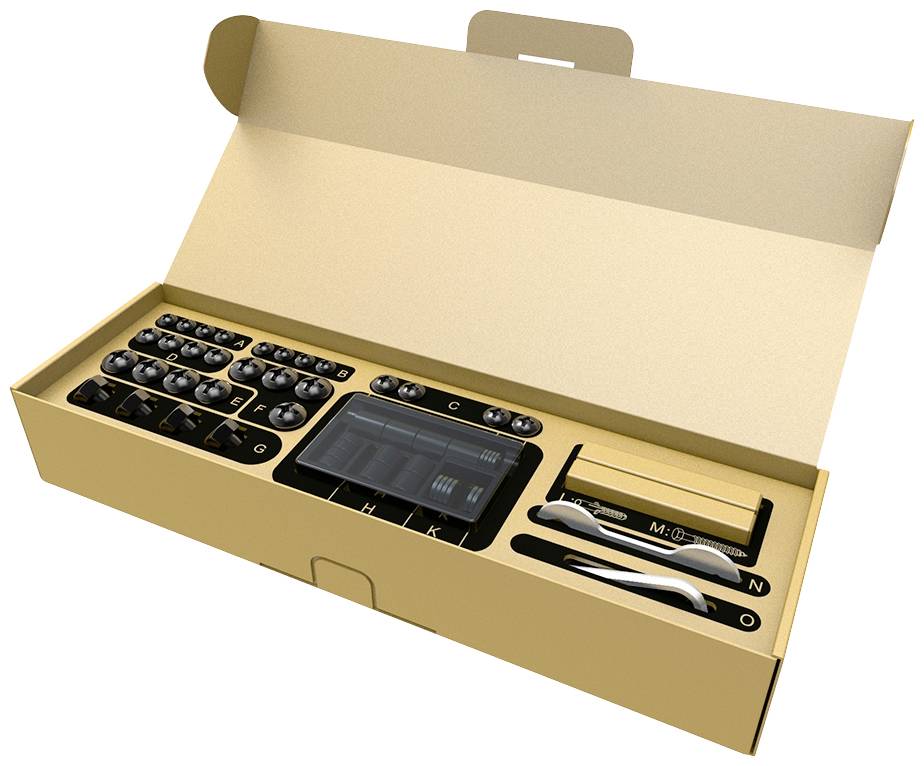 Opened packaging with electronic device, buttons, charging cable, and accessories. Contains alphabetical labels on individual parts.