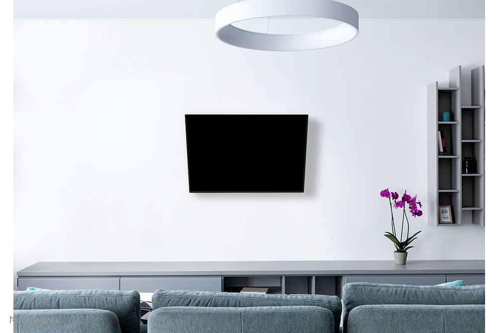 A modern living room with a grey sofa and television mounted on the white wall. A pink orchid sits on a sideboard beneath the TV.