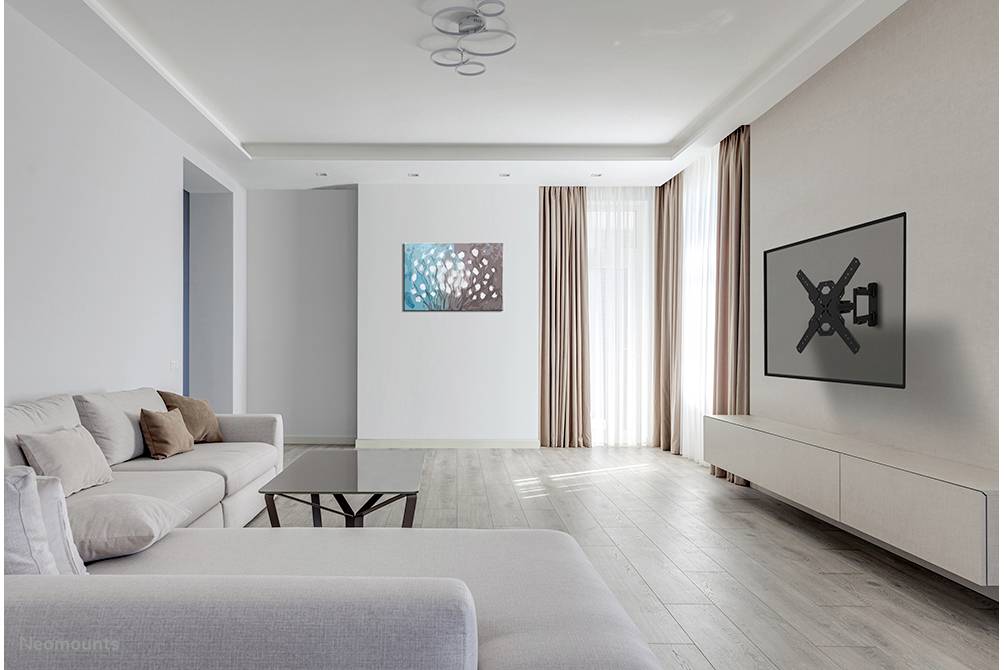 Modern living room with a grey sofa, coffee table and wall mounting without a TV. A painting and long curtains adorn the walls.