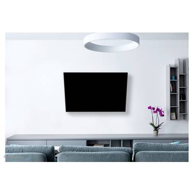 A modern living room with a large, black flatscreen television mounted on the white wall. In the foreground are blue sofas. To the right, a vase contains a purple orchid.