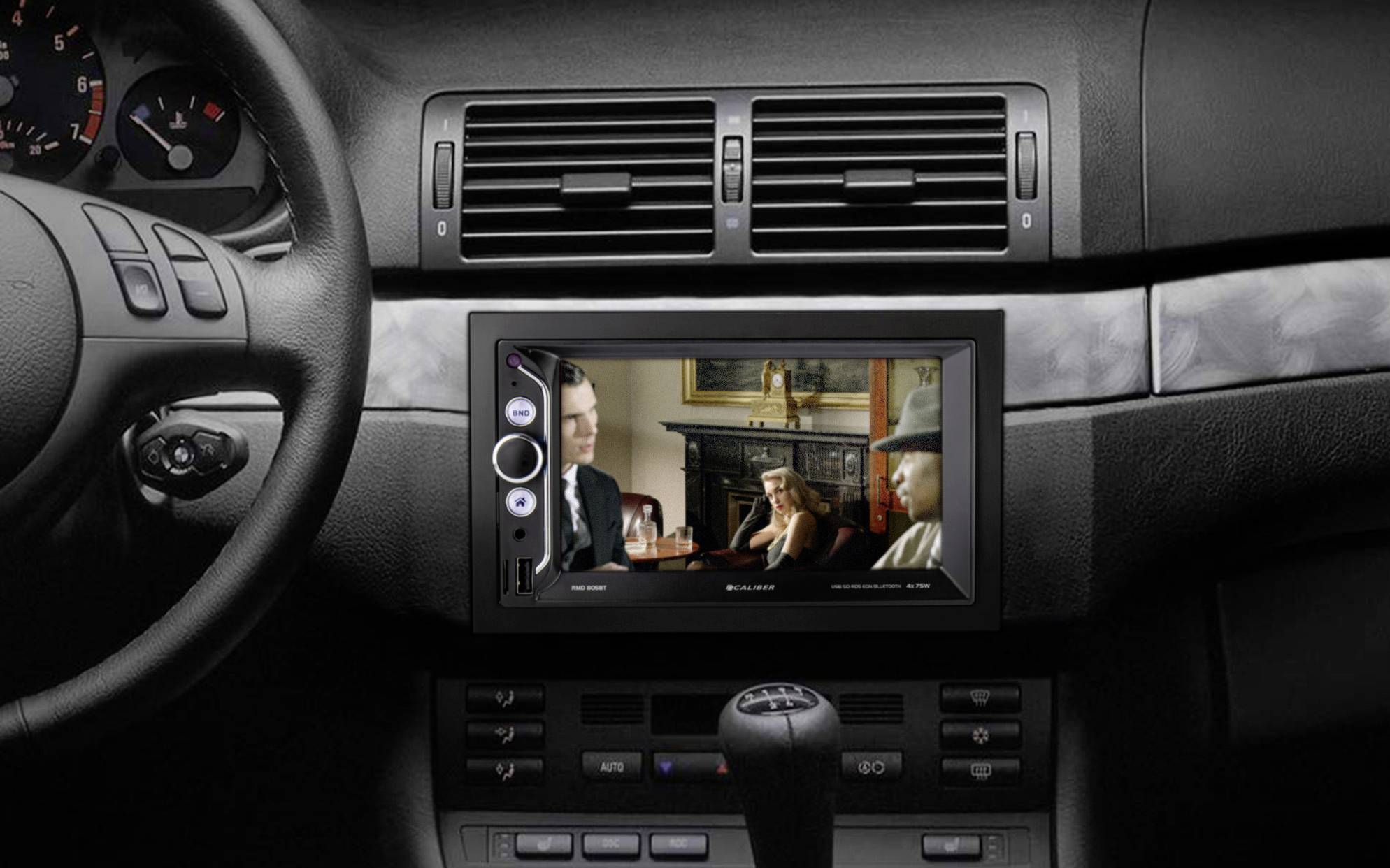 Satellite navigation system in a car with a film playing on the screen. Steering wheel and dashboard are visible.