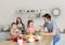 Family in a modern kitchen: Father and daughter cooking together, mother and son bringing ingredients. Cheerful atmosphere during shared cooking.