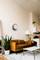A living room with a brown leather sofa, a white coffee table and a large plant. A modern wall unit is hanging on the wall.
