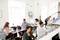 A group of people are working in a modern office with laptops and papers. The bright, open-plan layout promotes productivity.