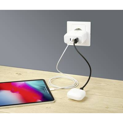 A mobile phone is connected to a power socket via a USB cable with a charger, whilst it rests on a wooden table.