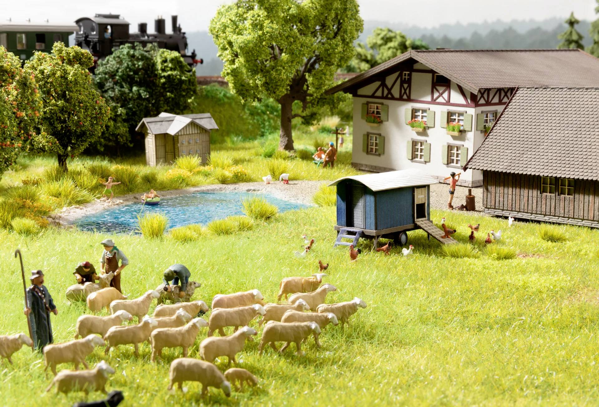 Miniature landscape featuring a farmstead, a cattle herder with sheep, a pond, chickens and a moving train in the background.