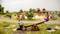 A miniature model of a playground shows two children sitting on a seesaw, surrounded by other play equipment and trees.