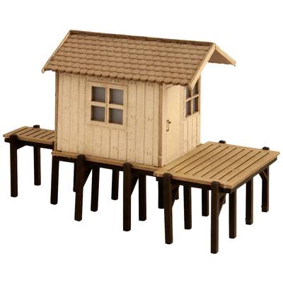 A small, wooden model house stands on stilts. It has a gabled roof, a window on the front, and is surrounded by a platform.