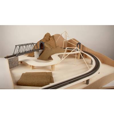 Model of a miniature railway landscape with bridges, a tunnel and a mountain made from cardboard and wood. Railway tracks run across the structure.