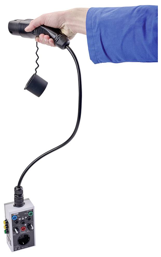 A hand is holding a black device with a cable, from which a grey console with colourful buttons and a slot is hanging.