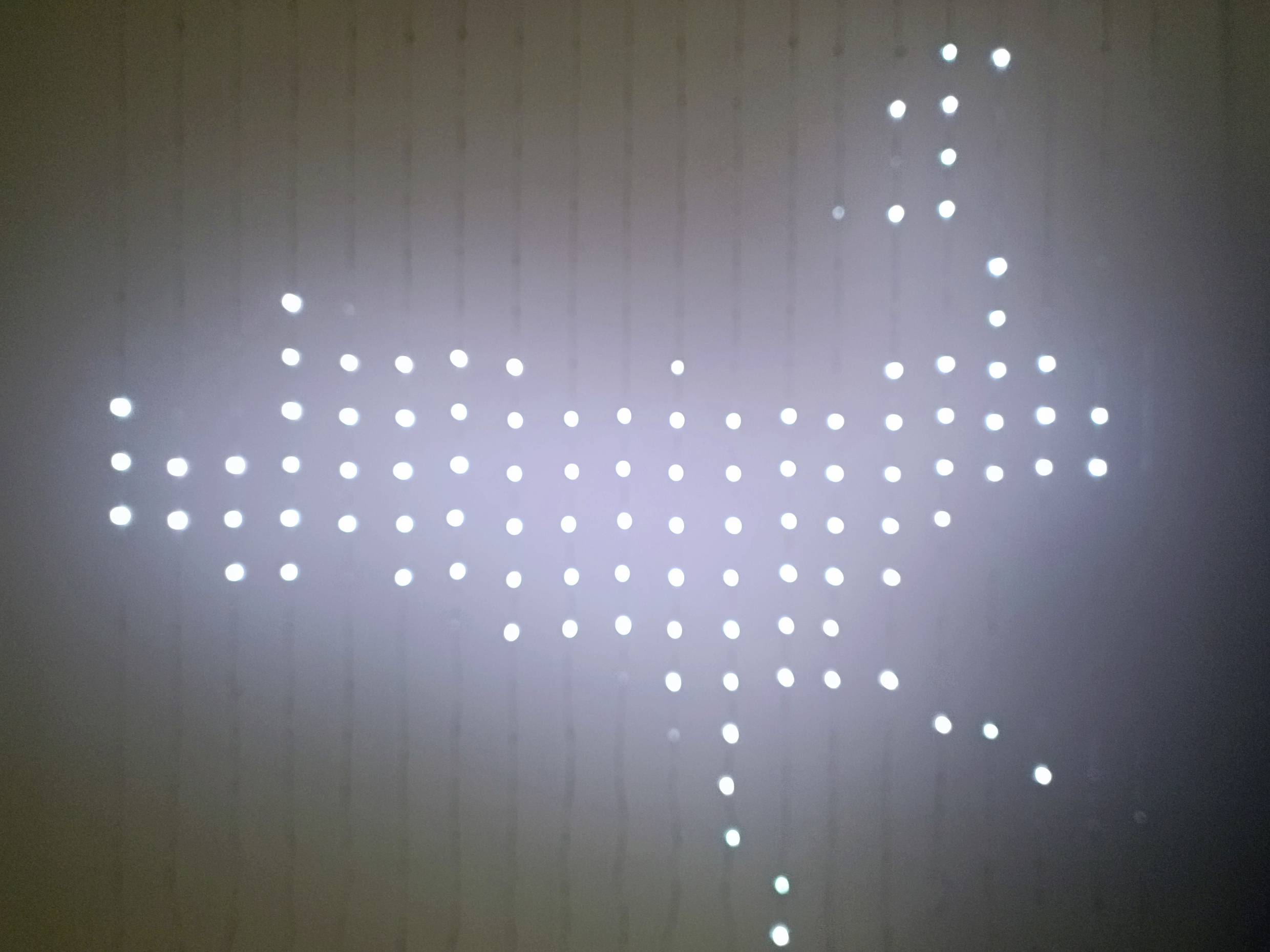 A luminous dot matrix outlines the shape of an animal on a dark background, reminiscent of a reindeer.