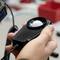 A hand holds a light meter, a device used to measure brightness. Blurred laboratory environment in the background.