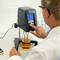 A scientist in a laboratory is measuring the viscosity of a liquid using a viscometer. The measurement value is displayed on the device.