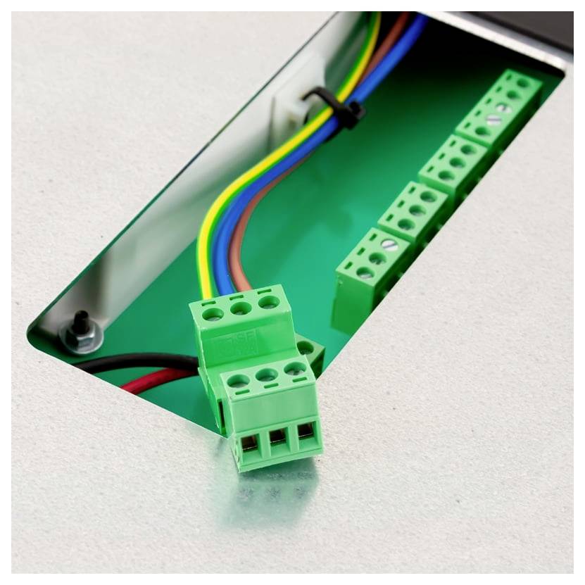 Close-up of an electrical terminal block with multicolored wires connected through a metal panel opening.<br>