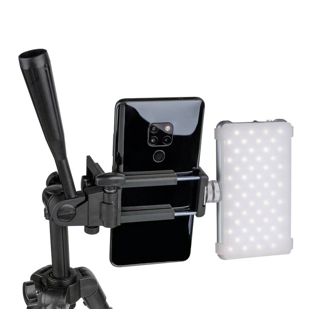 A smartphone is secured in a camera tripod mount, with an LED light beside it.