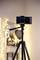 A smartphone is mounted on a tripod. In the background, out-of-focus, warm lights can be seen creating a cosy atmosphere.