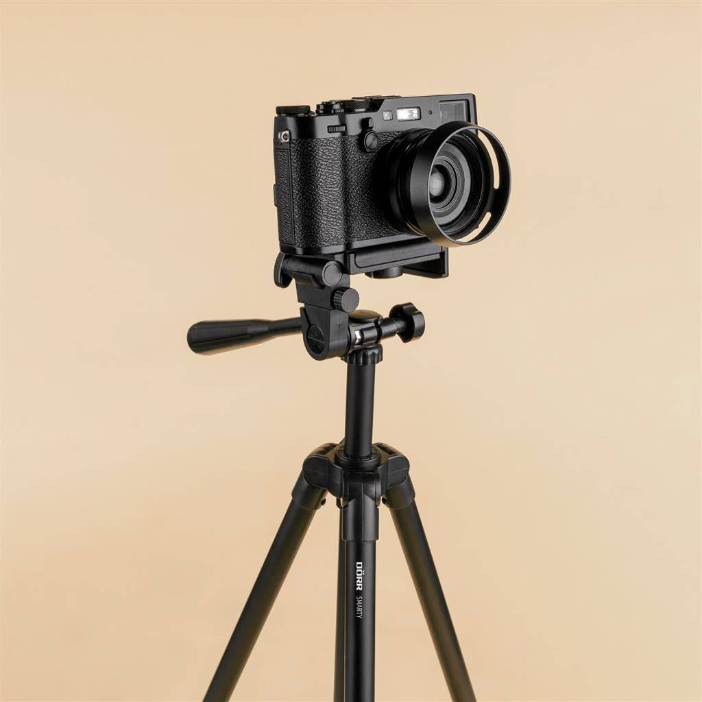 A black camera on a tripod against a beige background.
