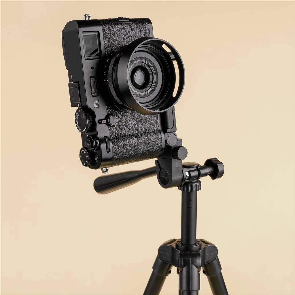 A black camera on a tripod against a beige background. It is oriented towards the left.
