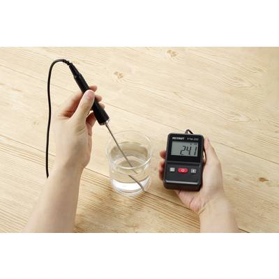 A person is measuring the water temperature in a glass with a digital thermometer, which displays 24.1 degrees.