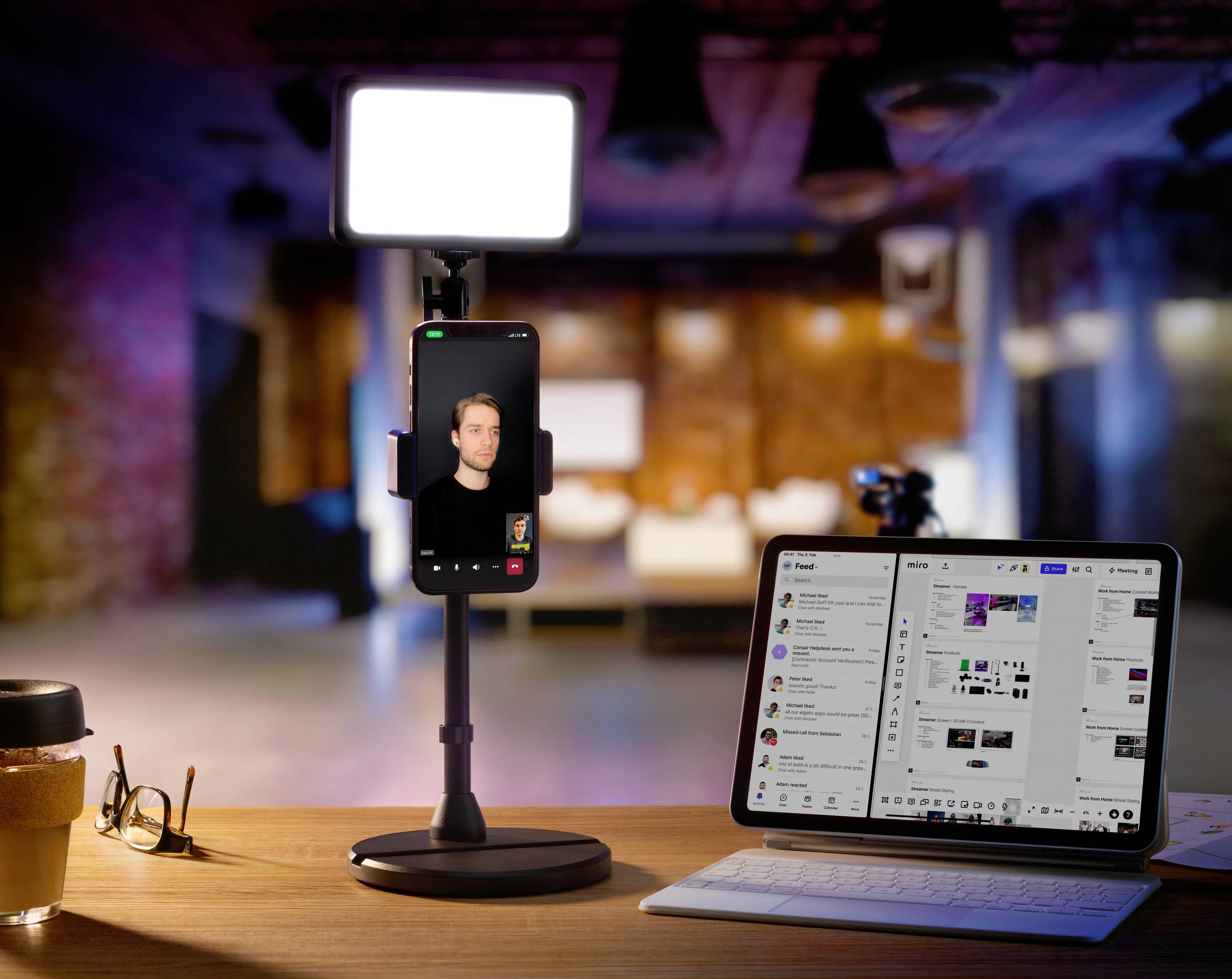 A smartphone on a table displays a video recording; next to it a tablet with communication software open and an illuminated background.
