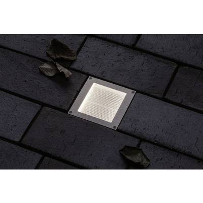 Paving stones with an integrated, illuminated ground spotlight and two dry leaves at the edges.