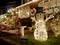 A illuminated snowman stands in front of a festively decorated house with Christmas lighting and decorations in the garden.