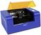A blue laser engraver with an open lid reveals its internal mechanism. An orange cover is visible at the top.