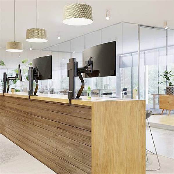 Office environment with modern, glass partitions, wooden desks and large monitors; Bright, welcoming lighting.