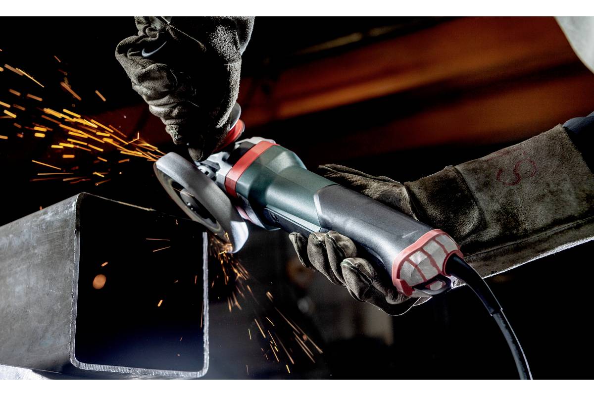 A person is using an angle grinder to work with metal. Sparks are flying from the point of contact. The person is wearing protective gloves.