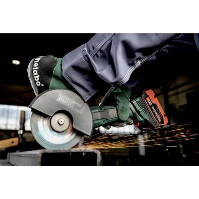 A worker is using an angle grinder to cut a metal element. Sparks are flying in a workshop.