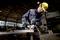 A worker in protective clothing and a hard hat is grinding metal in a workshop, with sparks flying.