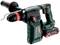 A green hammer drill with a red and black handle, brand name "Metabo", with an auxiliary grip on the left side and battery compartment on the right side.