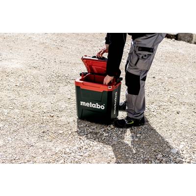 A person opens a Metabo toolbox outdoors on a gravel surface.