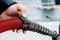 A person is holding a red electric charging nozzle, demonstrating the process of vehicle charging.