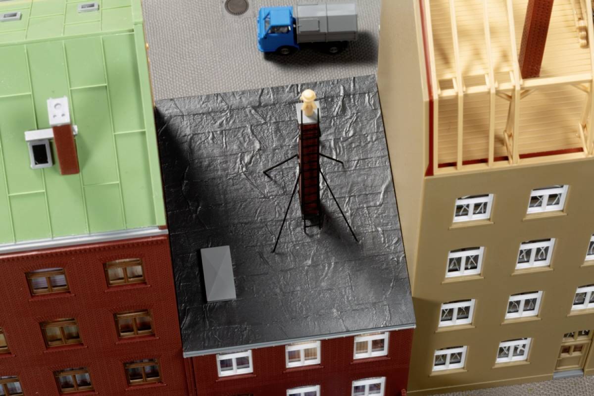 Model of an urban scene with buildings, including one with a green roof. A lorry is parked on the street.