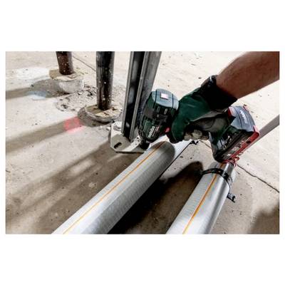 A person wearing gloves uses a power tool to secure metal pipes on a floor. The pipes have yellow lines and are clamped together.