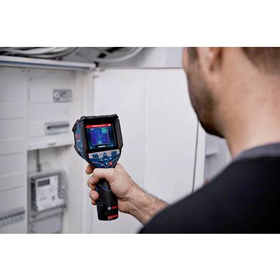A person is using a thermal imaging camera to check the temperature of an electrical control panel.